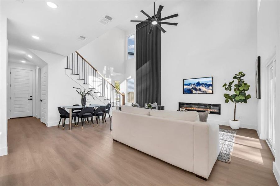 Living room featuring a high ceiling, light hardwood / wood-style flooring, and ceiling fan