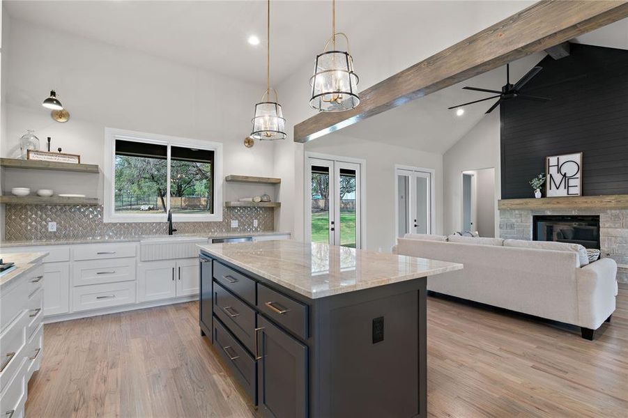 Kitchen with a center island, white cabinetry, decorative light fixtures, decorative backsplash, and light hardwood / wood-style flooring