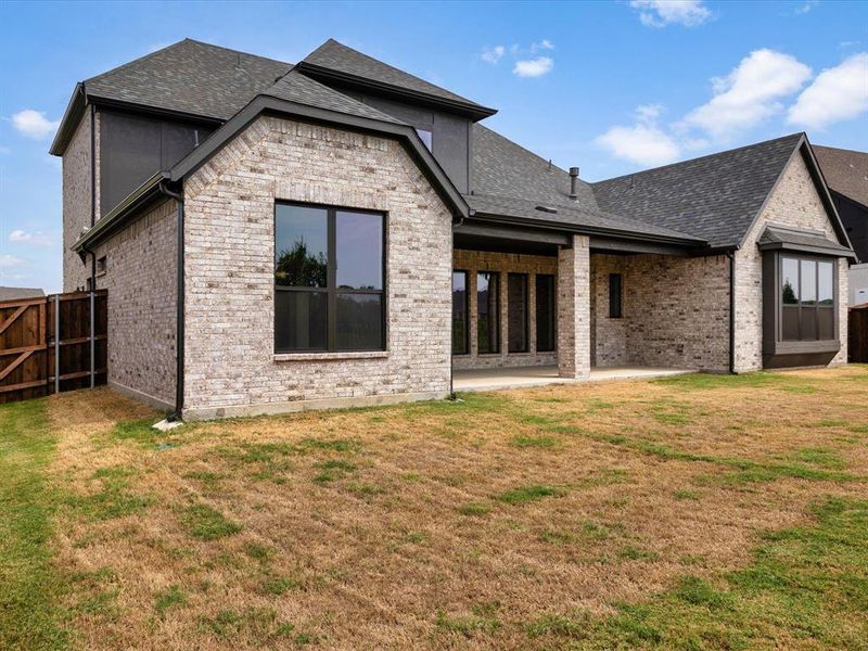 Back of house featuring a patio, brick siding, and a shingled roof