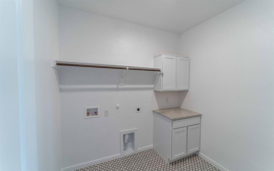 Laundry area featuring white cabinetry, a light-colored countertop, and a decorative tile floor