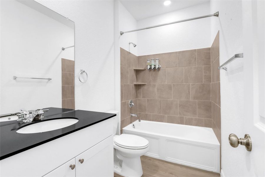 Bathroom featuring vanity, shower / bath combination, and light wood-style floors