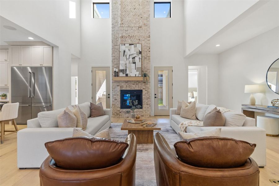 Here, your living room comes together around the fireplace, with balanced seating that makes conversation feel easy and intentional. Tall windows and double-height ceilings flood the room with natural light, giving the entire space an airy, elevated feel throughout the day.