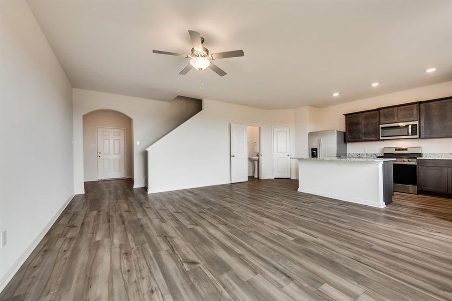 Kitchen with stainless steel appliances, wood-type flooring, a center island, ceiling fan, and dark brown cabinetry