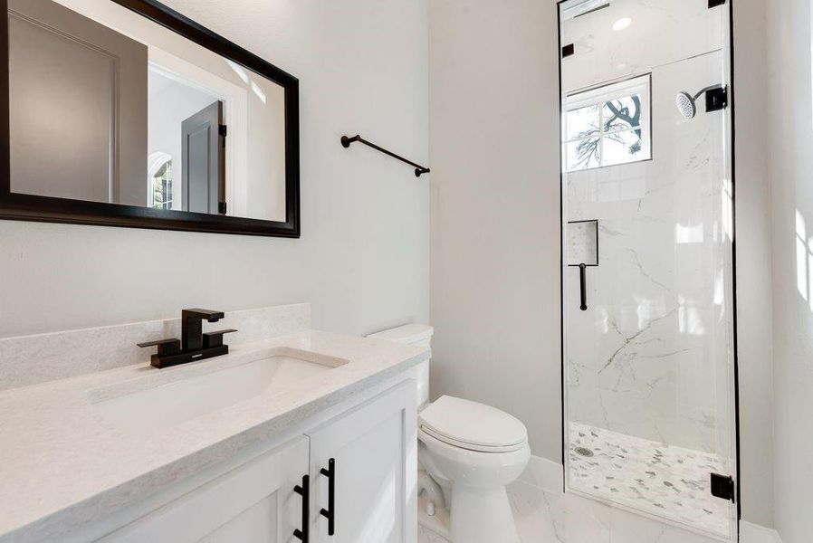 Bathroom with toilet, a shower with shower door, and vanity