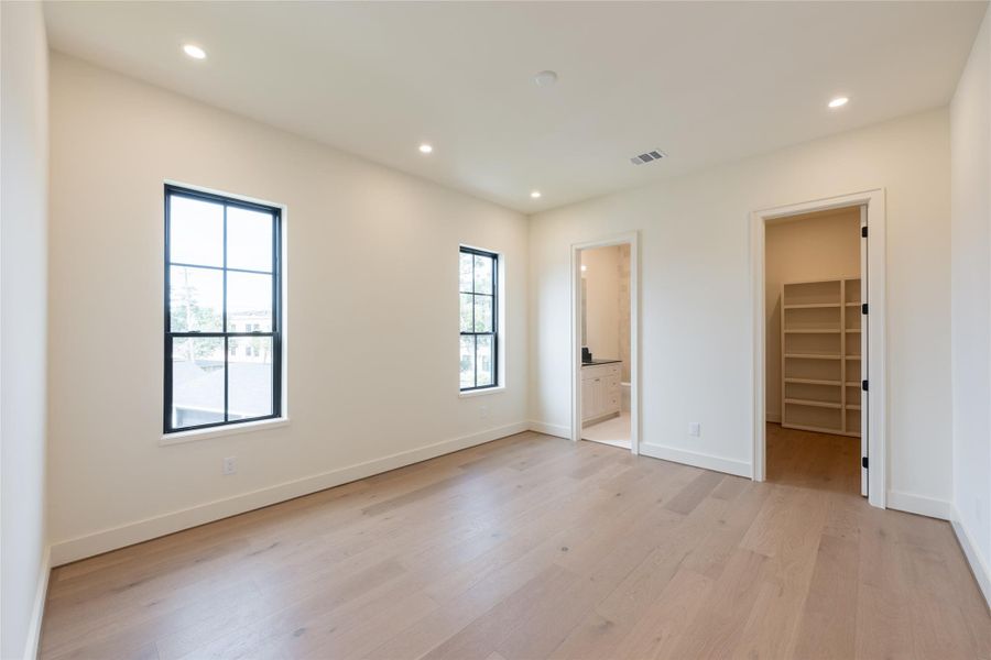 This spacious secondary bedroom features wide-plank European white oak floors, black-framed windows, and direct access to a walk-in closet and en-suite bath. Natural light pours in, creating an airy atmosphere that complements the clean, transitional design. This spacious secondary bedroom features wide-plank European white oak floors, black-framed windows, and direct access to a walk-in closet and en-suite bath. Natural light pours in, creating an airy atmosphere that complements the clean, transitional design.