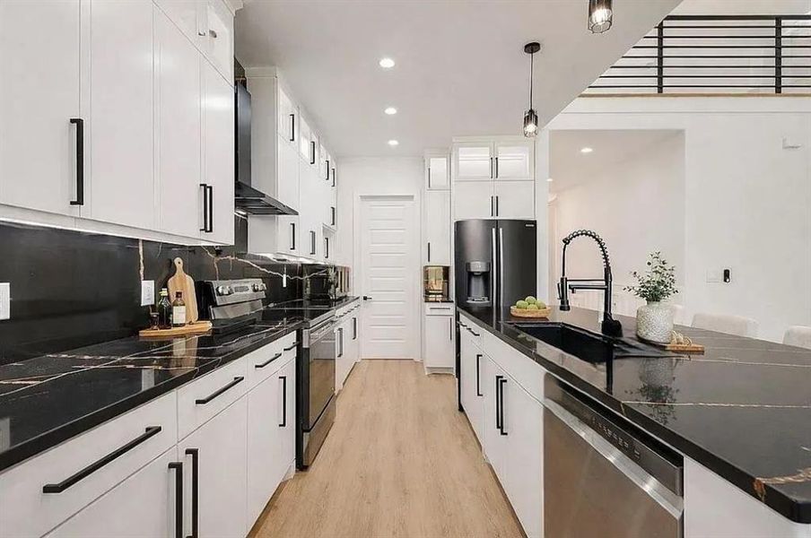 Contemporary kitchen featuring dark countertops with light veining, white cabinetry, and matte black hardware