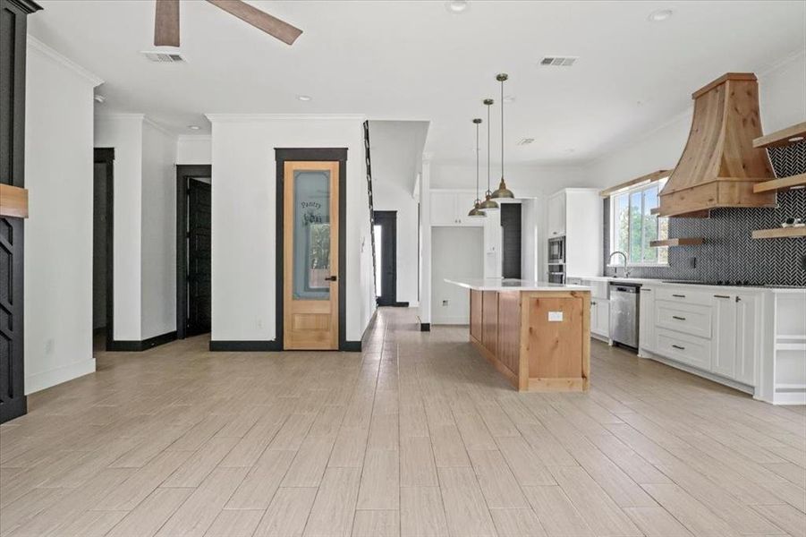 Kitchen featuring open shelves, white cabinets, decorative backsplash, crown molding, and light wood-type flooring