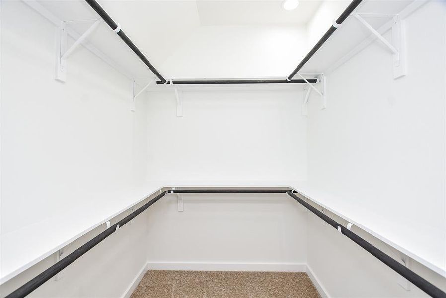 Spacious walk-in closet in the secondary bedrooms, offering ample storage with built-in shelving and double hanging rods. Designed for both functionality and organization.