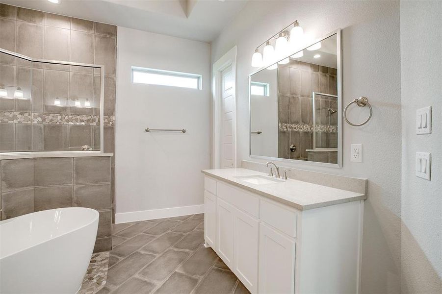 Bathroom with a bathtub, tile flooring, and vanity with extensive cabinet space