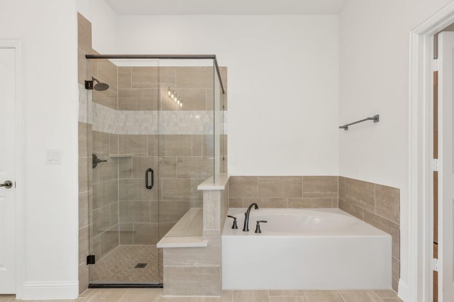Bathroom with glass-enclosed walk-in shower and soaking tub with beige tile surround and dark fixtures Bathroom with glass-enclosed walk-in shower and soaking tub with beige tile surround and dark fixtures
