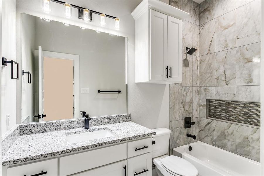 Full bathroom with vanity, tiled shower / bath combo, and toilet