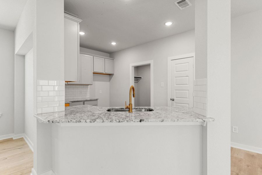 This modern kitchen showcases elegant finishes, light cabinetry, and a spacious wraparound counter with a stylish gold faucet. The open design allows for a smooth connection to the surrounding living areas, enhancing both functionality and flow. This modern kitchen showcases elegant finishes, light cabinetry, and a spacious wraparound counter with a stylish gold faucet. The open design allows for a smooth connection to the surrounding living areas, enhancing both functionality and flow.