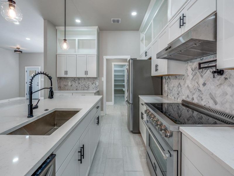 Kitchen featuring high end stainless steel range, white cabinets, and light stone counters