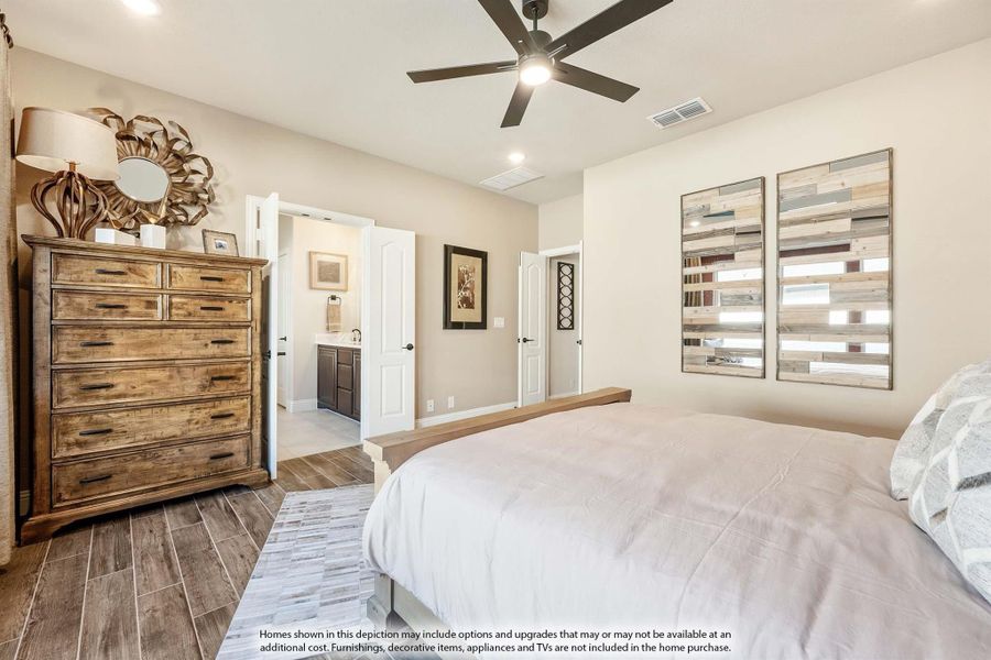 Bedroom with wood-look tile floors, ceiling fan, wooden dresser, and open door to ensuite bathroom Bedroom with wood-look tile floors, ceiling fan, wooden dresser, and open door to ensuite bathroom