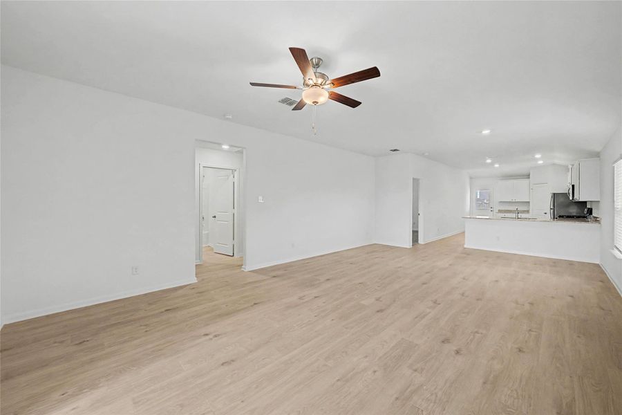 A well-lit, open-concept living space with light wood flooring flows seamlessly into a modern kitchen.