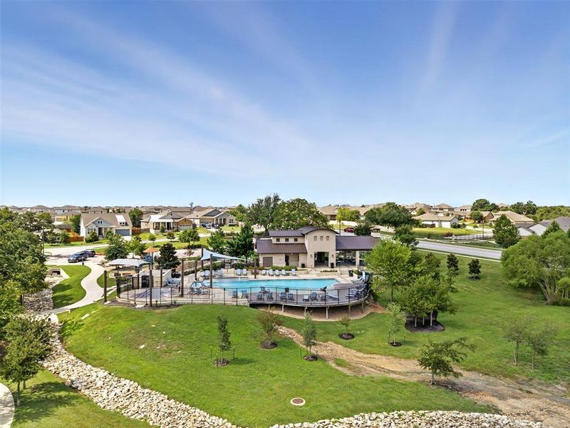 An aerial perspective showcases a vibrant community clubhouse surrounded by green spaces.