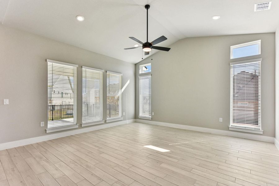 Unfurnished room featuring healthy amount of natural light, lofted ceiling, light wood-style floors, ceiling fan, and recessed lighting