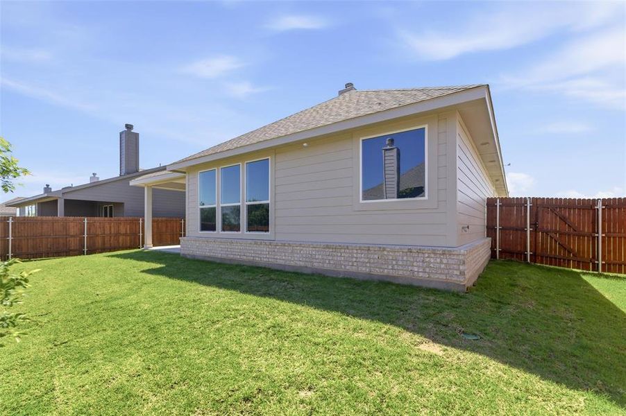 Rear view of property with a shingled roof, a fenced backyard, a gate, and a patio area