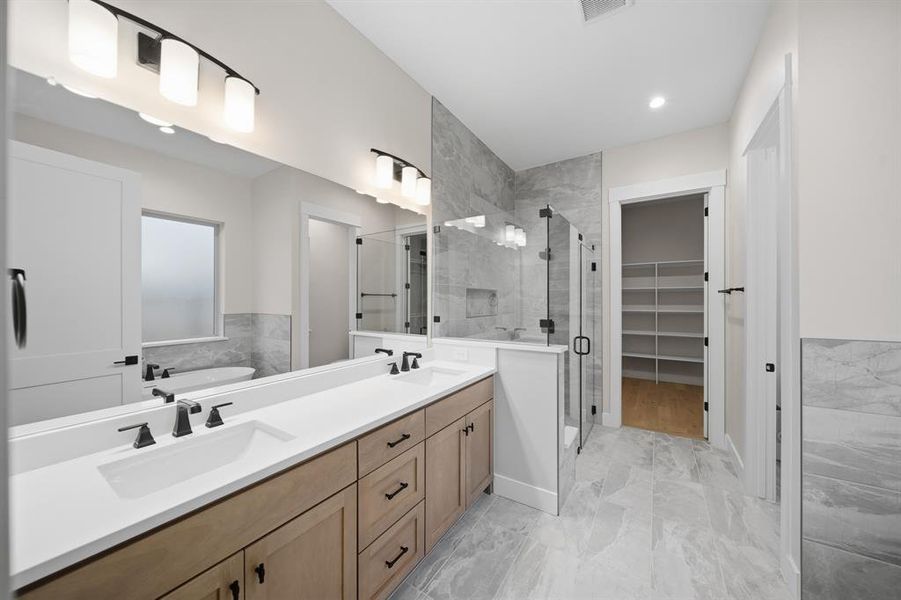 Bathroom featuring light marble finish flooring, double vanity, a spacious closet, a stall shower, and a tub to relax in Bathroom featuring light marble finish flooring, double vanity, a spacious closet, a stall shower, and a tub to relax in