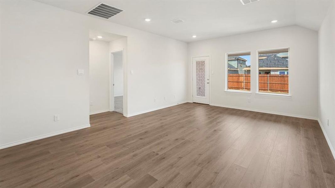 Spacious room featuring wood-finish flooring, recessed lighting, and multiple windows