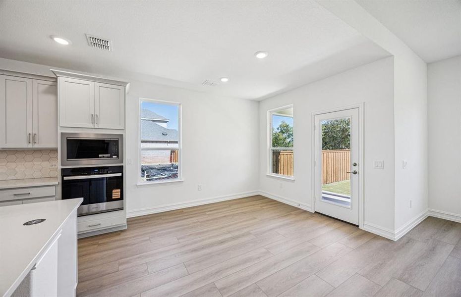 Open kitchen with adjoining nook featuring large windows and direct access to the backyard Open kitchen with adjoining nook featuring large windows and direct access to the backyard