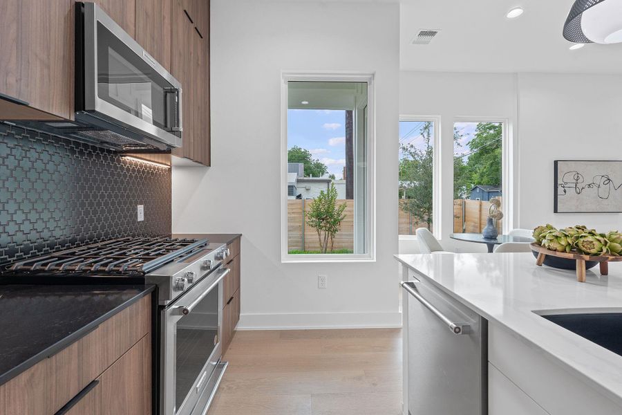 Kitchen featuring stainless steel appliances, modern cabinets, light wood-style flooring, tasteful backsplash, and recessed lighting