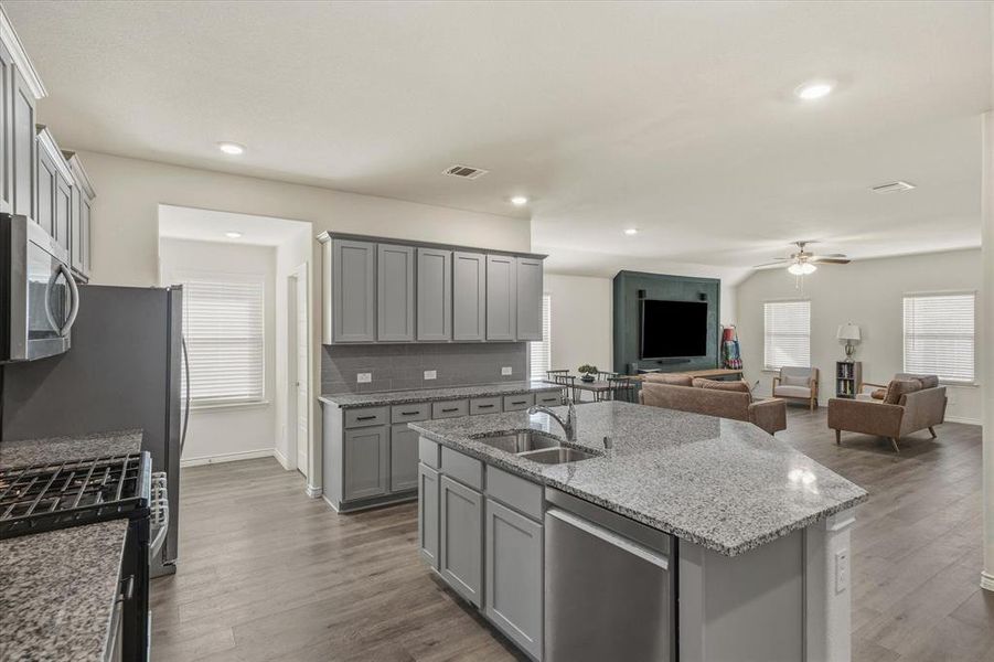 Kitchen featuring stainless steel appliances, gray cabinetry, light stone counters, open floor plan, and recessed lighting Kitchen featuring stainless steel appliances, gray cabinetry, light stone counters, open floor plan, and recessed lighting