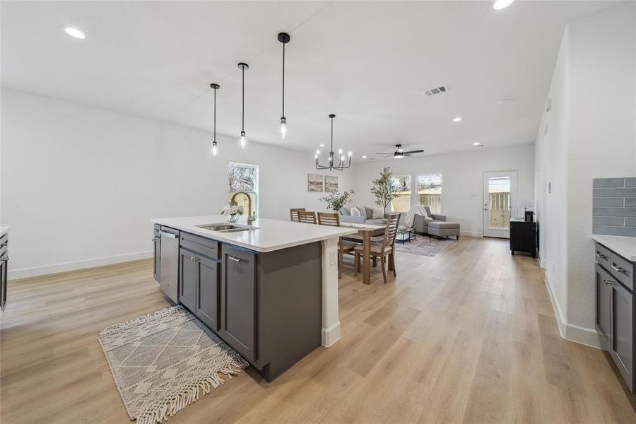 Kitchen featuring sink, pendant lighting, a kitchen island with sink, and light hardwood / wood-style flooring