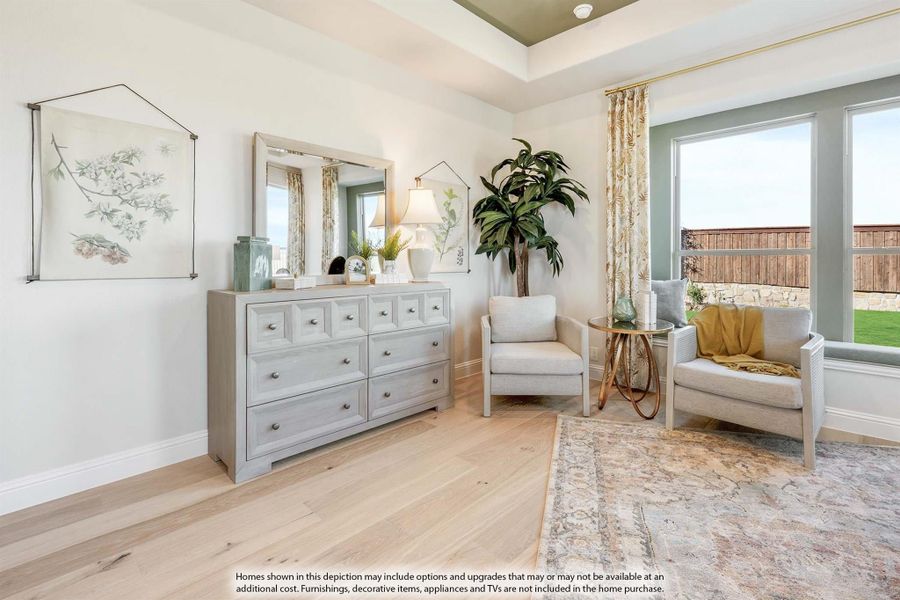 Bedroom sitting area with gray dresser, two accent chairs, and large windows with natural light