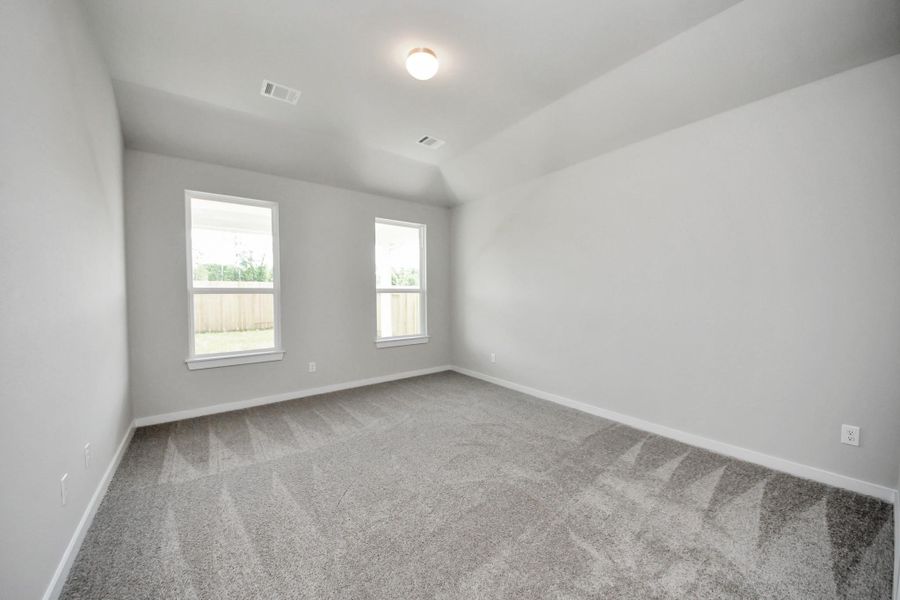 Escape and relax in the exquisite primary suite, a haven to unwind after a long day. The spacious room, located on first floor, boasts plush carpeting, soothing paint tones, high ceilings, and expansive windows adorned with privacy blinds. Sample photo of completed home with similar floor plan. Actual colors and selections may vary.