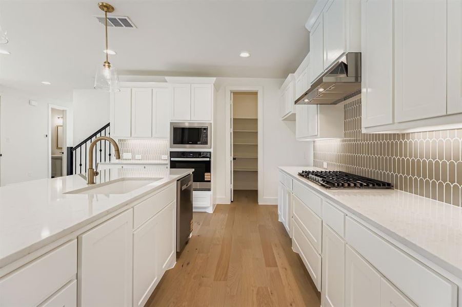 Kitchen with stainless steel appliances, under cabinet range hood, tasteful backsplash, white cabinets, and recessed lighting