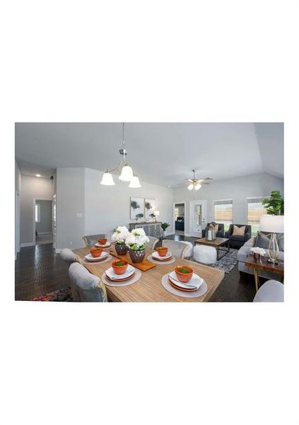 Dining area featuring ceiling fan with notable chandelier and lofted ceiling