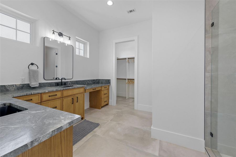 Spacious and serene primary bath featuring dual vanities, elegant lighting, and a dedicated makeup station. Clean lines and natural light create a relaxing, spa-like atmosphere to start and end your day in comfort.