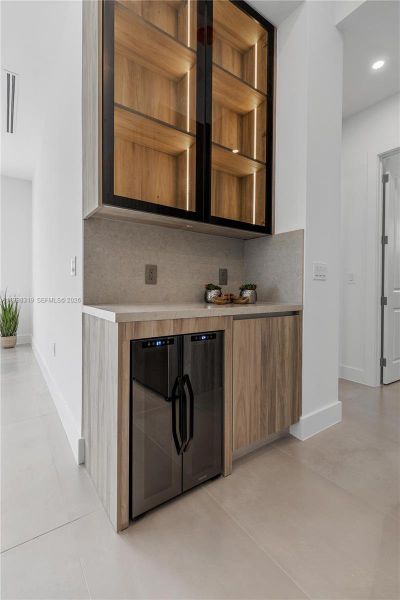 A DEDICATED BAR and COFFEE STATION with glass display cabinets, LED lighting, and a WINE COOLER elevate your hosting experience.