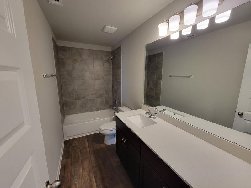 Full bath featuring toilet, visible vents, wood finished floors, and vanity