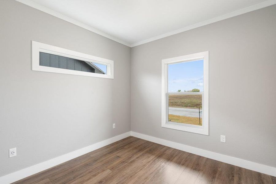Empty room with ornamental molding and wood finished floors