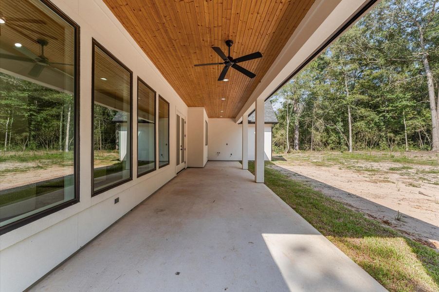 Covered back porch with wood-accent ceiling and LED lights, offering peaceful views of the expansive backyard. Covered back porch with wood-accent ceiling and LED lights, offering peaceful views of the expansive backyard.