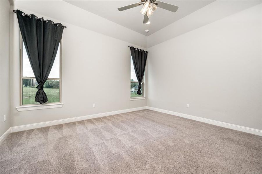 Carpeted spare room featuring ceiling fan and a healthy amount of sunlight