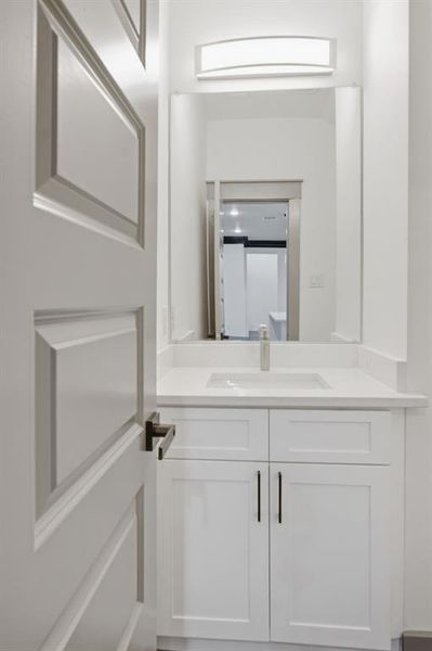 White shaker-style vanity with a light-colored countertop and integrated sink