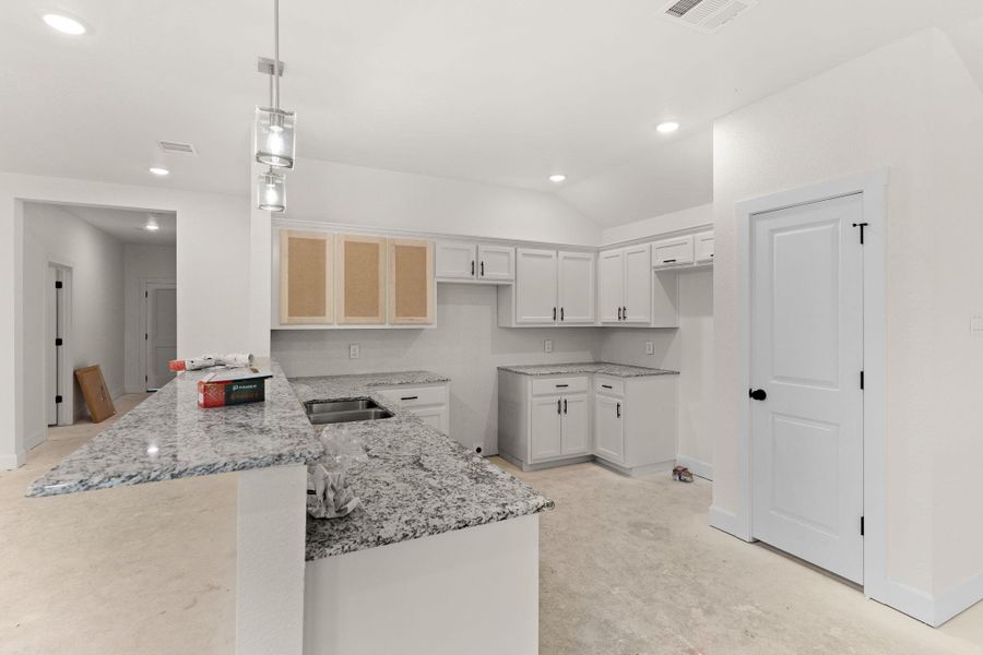 Kitchen featuring a peninsula, light stone countertops, recessed lighting, pendant lighting, and white cabinets Kitchen featuring a peninsula, light stone countertops, recessed lighting, pendant lighting, and white cabinets