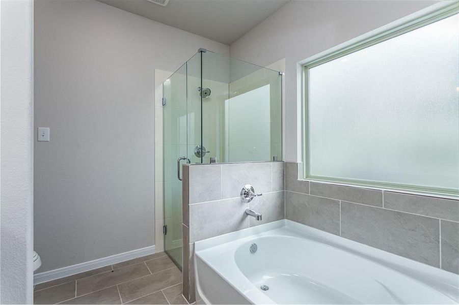 Unwind in the primary bathroom’s large soaking tub or refresh in the separate glass-enclosed shower. This space is designed with relaxation in mind, featuring modern tile work and sleek finishes that add a touch of elegance to your daily routine. **This image is from another Saratoga Home - Mockingbird floorplan.**