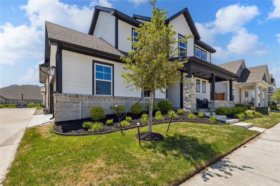 View of front facade featuring board and batten siding, roof with shingles, stone siding, and a front yard View of front facade featuring board and batten siding, roof with shingles, stone siding, and a front yard