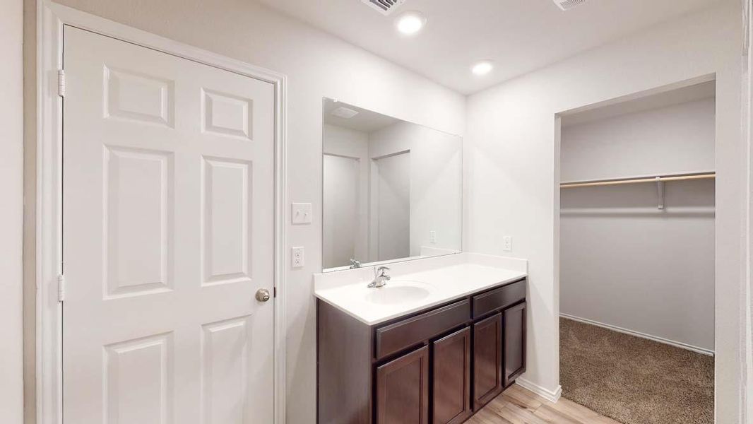 Bathroom vanity featuring a single basin sink, white countertop, and dark wood-finish cabinetry