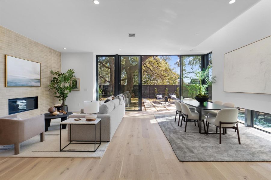 Wide plank white oak flooring, 8’ doors and 10’ ceilings are highlighted by a wall of floor to ceiling glass sliding doors overlooking the sparkling pool and private wood fenced yard