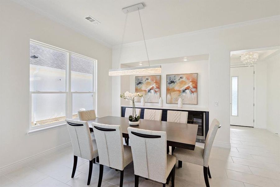 Dining space with wine cooler, an inviting chandelier, crown molding, and light tile floors