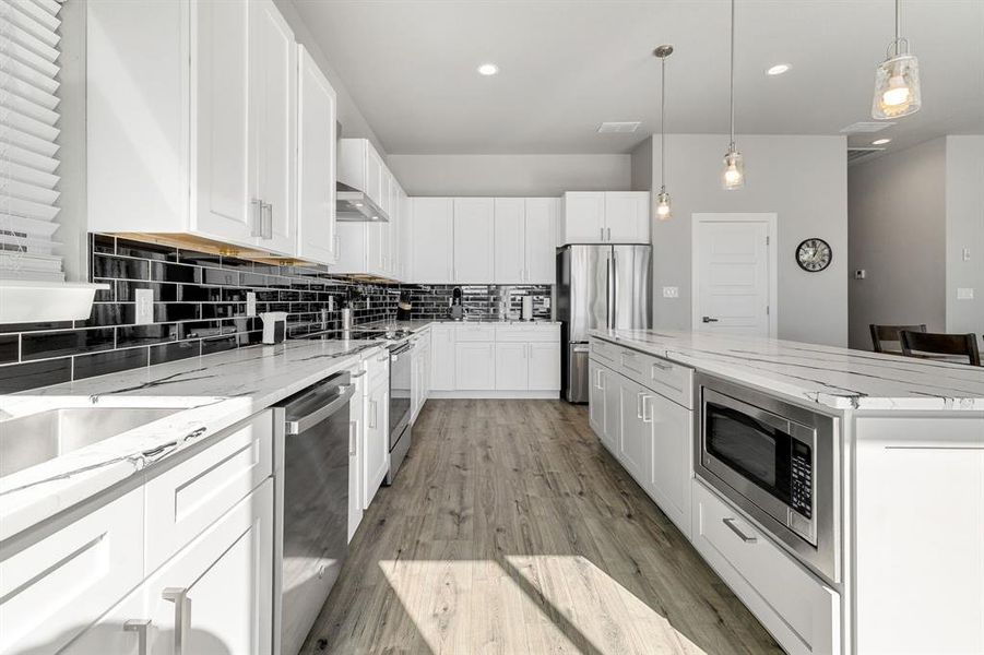 Kitchen with decorative backsplash, light stone countertops, white cabinetry, light wood-style flooring, and recessed lighting