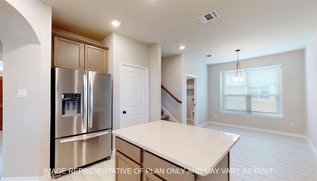 Kitchen featuring stainless steel fridge, a center island, pendant lighting, light stone counters, and recessed lighting Kitchen featuring stainless steel fridge, a center island, pendant lighting, light stone counters, and recessed lighting