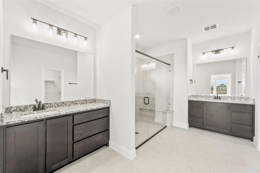 Master bathroom with dual vanities, dark wood cabinets, granite countertops, and glass walk-in shower Master bathroom with dual vanities, dark wood cabinets, granite countertops, and glass walk-in shower