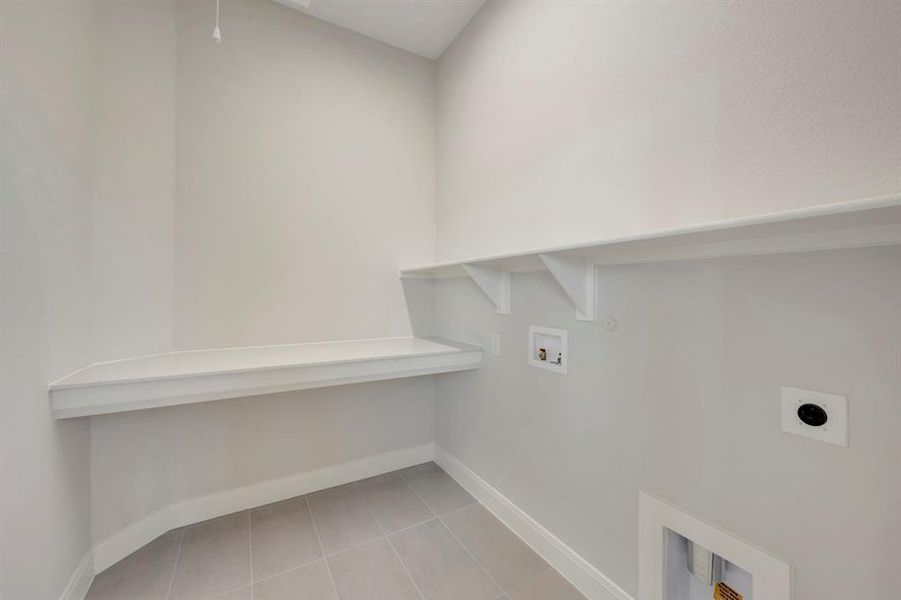 Laundry area with hookup for a washing machine, electric dryer hookup, light tile patterned floors, and hookup for a gas dryer