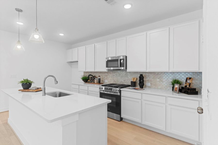 A beautiful kitchen design featuring white shaker cabinets, quartz countertops, and stainless-steel appliances—perfect for everyday meals or hosting family gatherings. This new CastleRock Communities home is a stunning ranch one story home Beautiful Ranch Style Home! The Pedernales Plan by CastleRock Communities! You will welcome your family and friends to Massey Oaks Community, a vibrant community with oak tree–lined streets, scenic walking trails, serene lakes, splash pad, and a wealth of amenities!